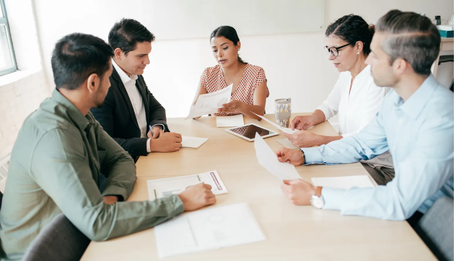 A team reviewing compliance documents together around a boardroom table