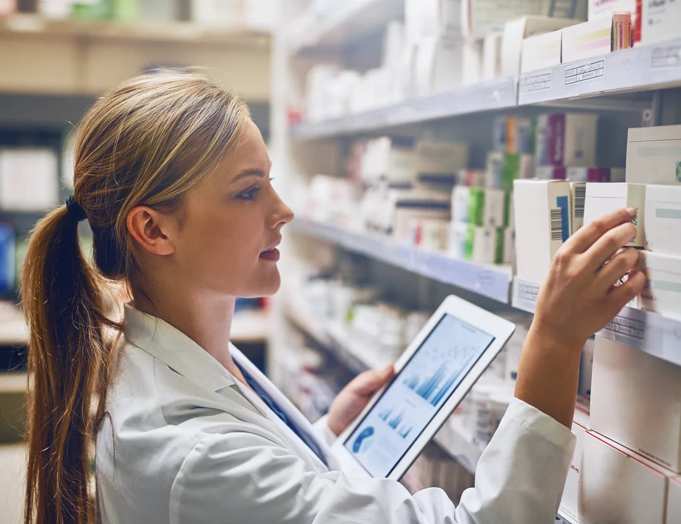 Healthcare professional reviewing inventory on a tablet in a pharmacy
