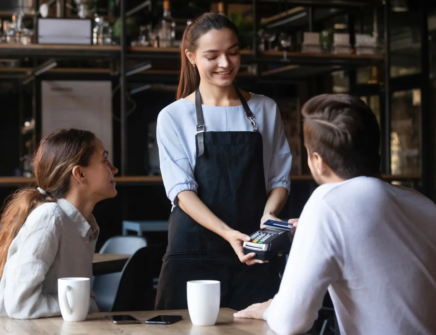 Customer making a contactless card payment at a restaurant POS terminal