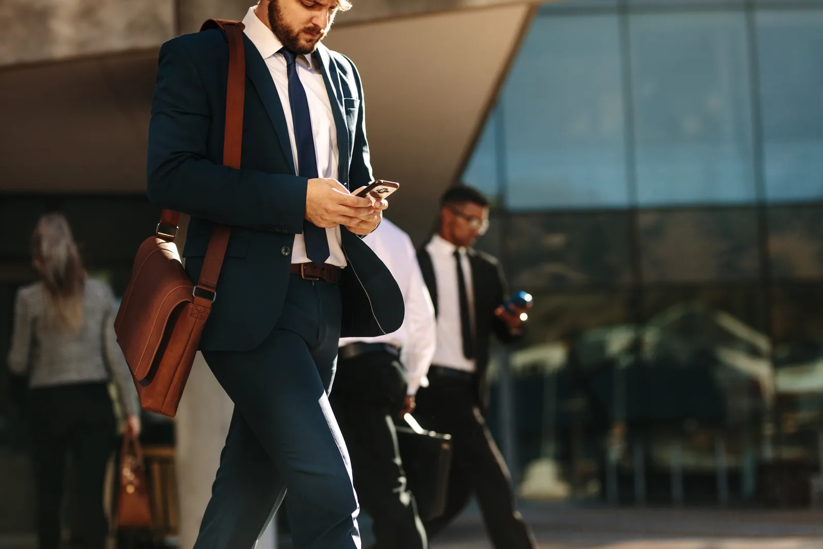A business professional checking their phone on the move in the city